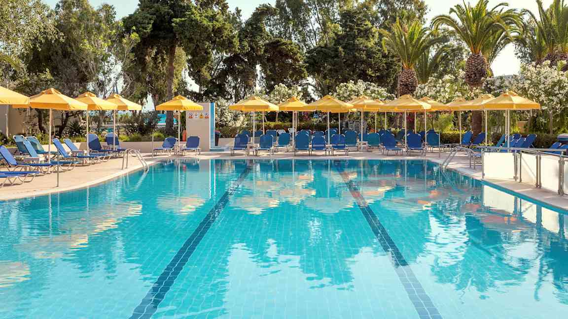 Utendørsbasseng med blått vann, omgitt av solsenger, parasoller og grønne trær. (AI-generert tekst)