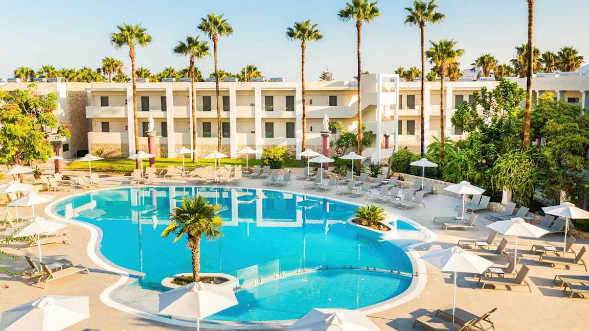 Bassengområde med solsenger, parasoller og hotellbyggninger i bakgrunnen. (AI-generert tekst)