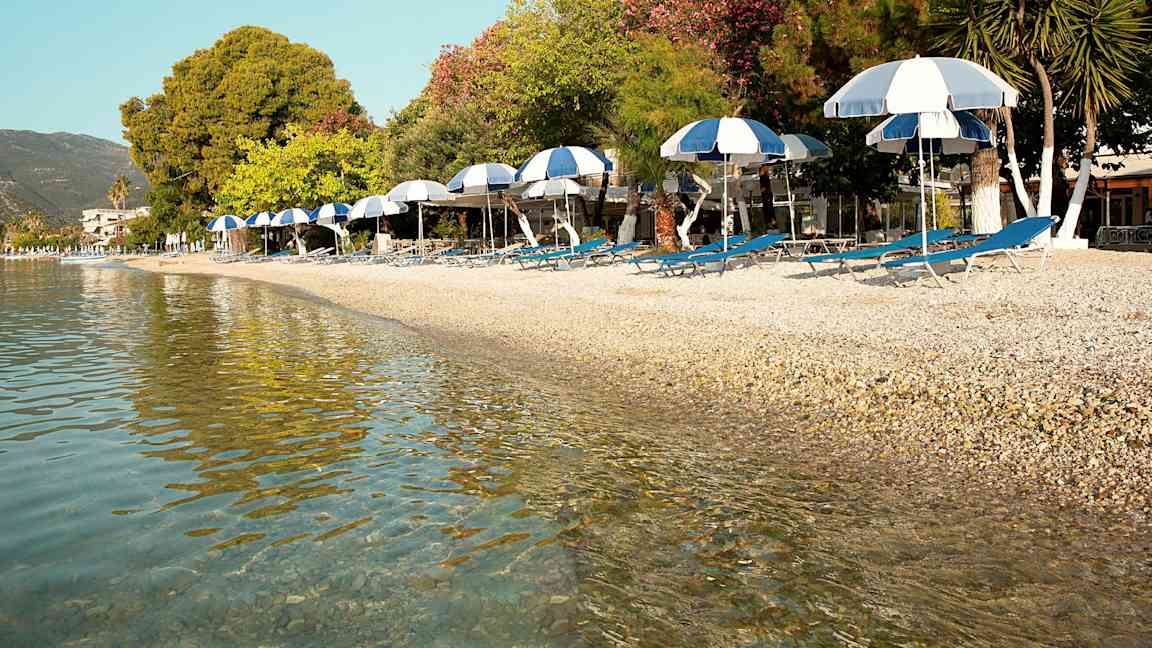 Strand med solsenger og parasoller ved vannet. (AI-generert tekst)