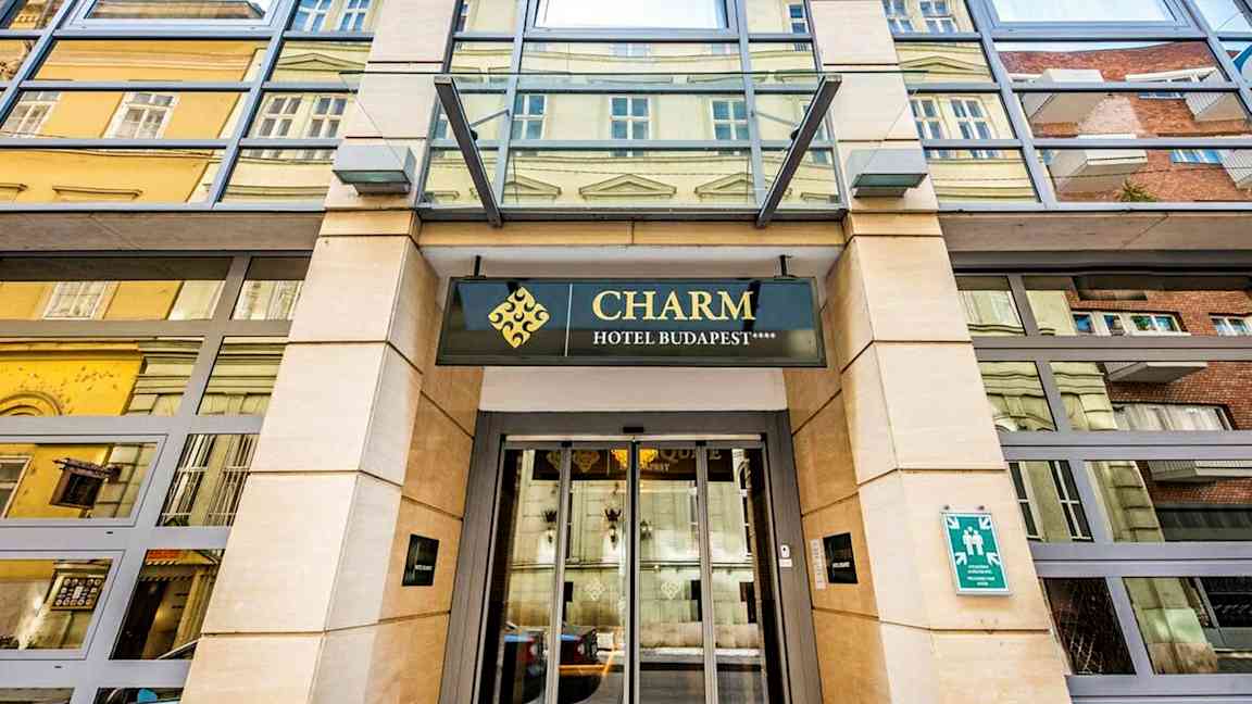 Inngang til et hotell med skiltet "Charm Hotel Budapest". (AI-generert tekst)