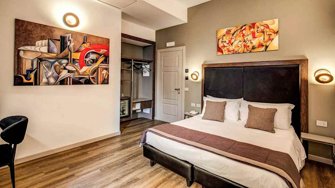 Et hotellrom med moderne innredning, en dobbeltseng og abstrakte kunstverk på veggene. (AI-generert tekst)