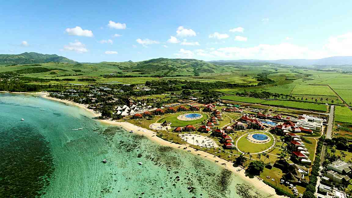 Luftfoto av en tropisk feriested ved kysten, med bassenger og grønne omgivelser. (AI-generert tekst)