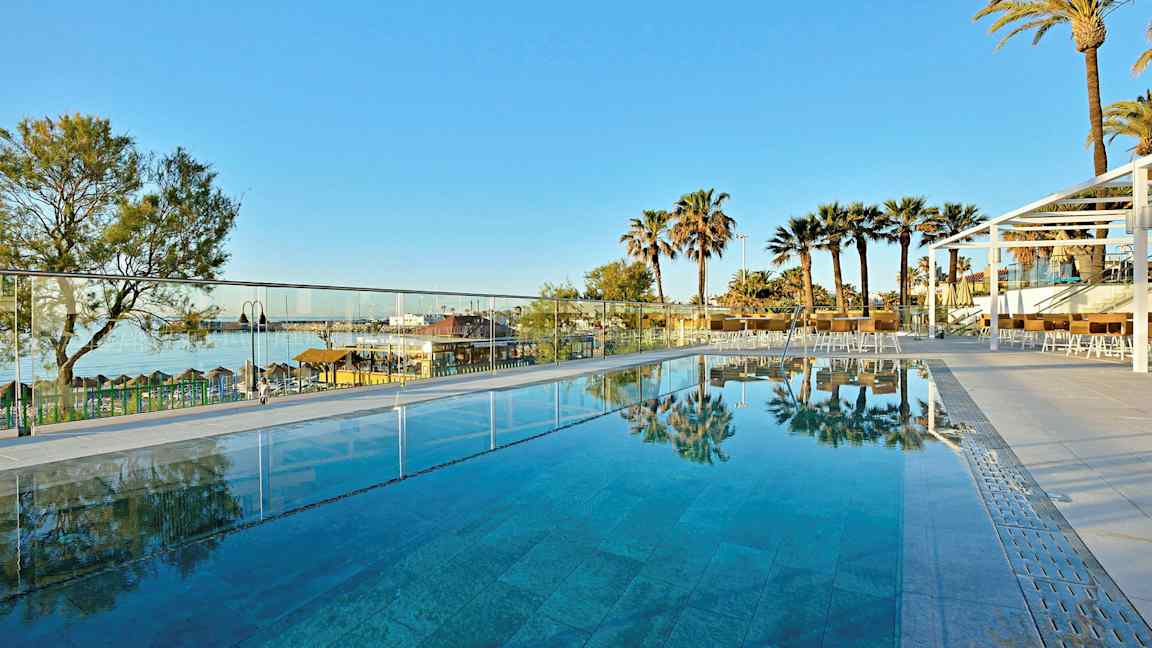 Utendørs basseng med utsikt over palmer og en klar blå himmel. (AI-generert tekst)