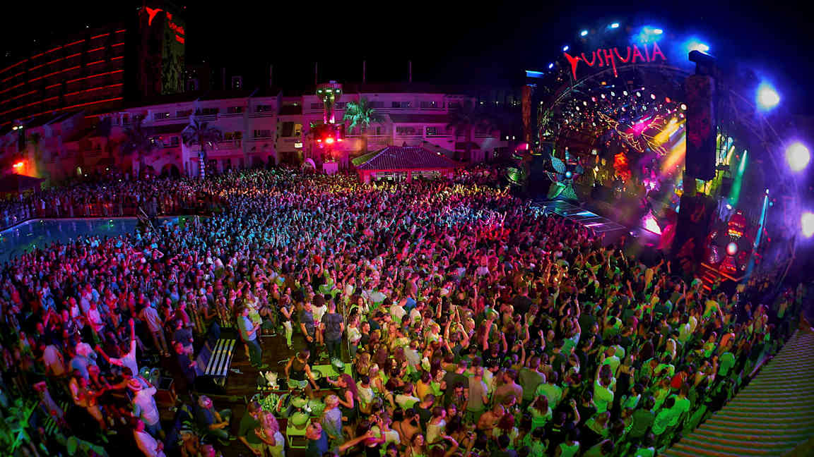 En nattklubb med et publikum foran en fargerikt opplyst scene. (AI-generert tekst)