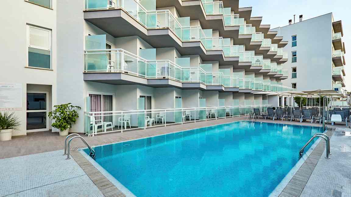 Hotellfasade med balkonger og basseng i forgrunnen. (AI-generert tekst)