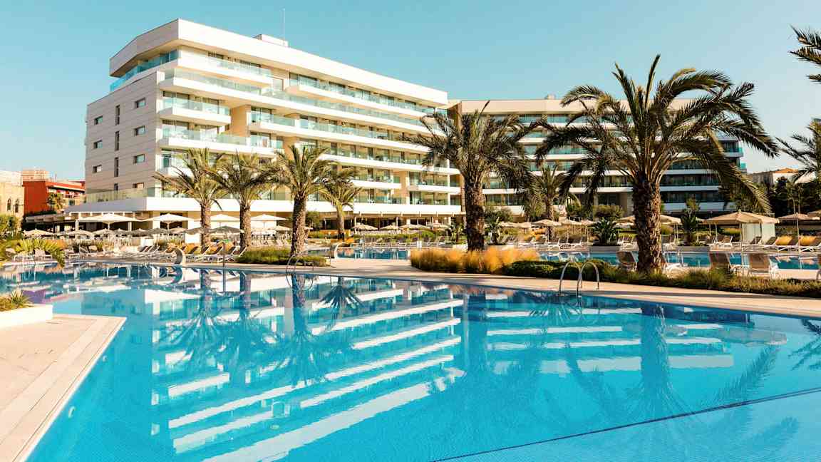 Hotell med basseng og palmer i et solrikt område. (AI-generert tekst)