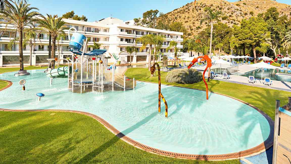 Barnebasseng med vannlek og hotellbygning i bakgrunnen. (AI-generert tekst)