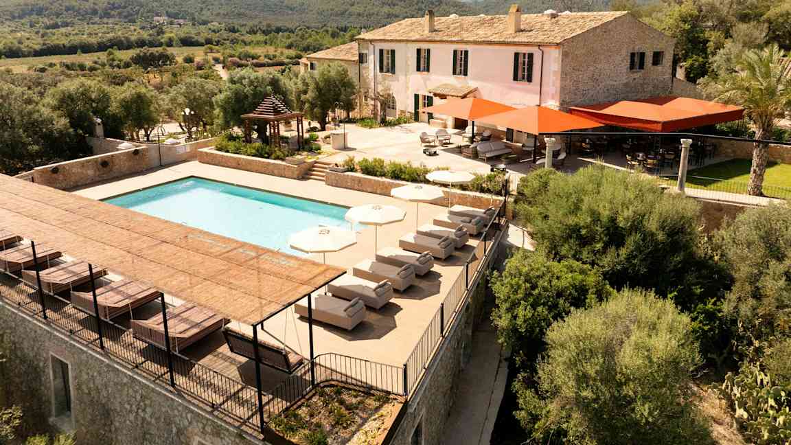 En villa med basseng og terrasse omgitt av grøntområder og åser. (AI-generert tekst)