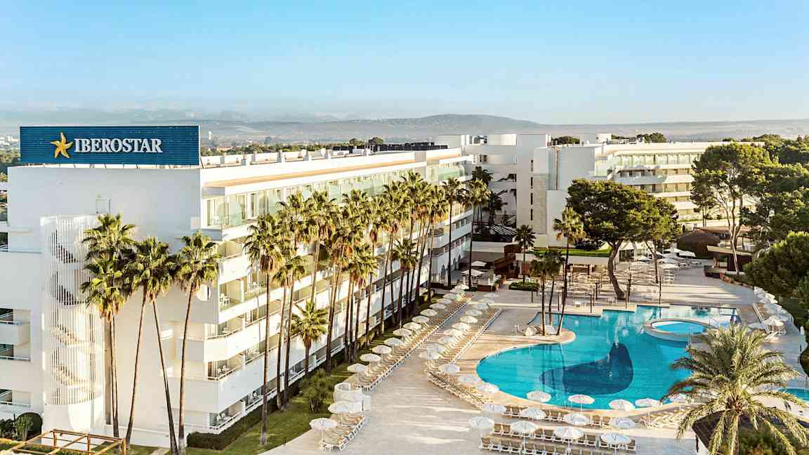 Et moderne hotell omgitt av palmer med et stort, klart blått basseng. (AI-generert tekst)