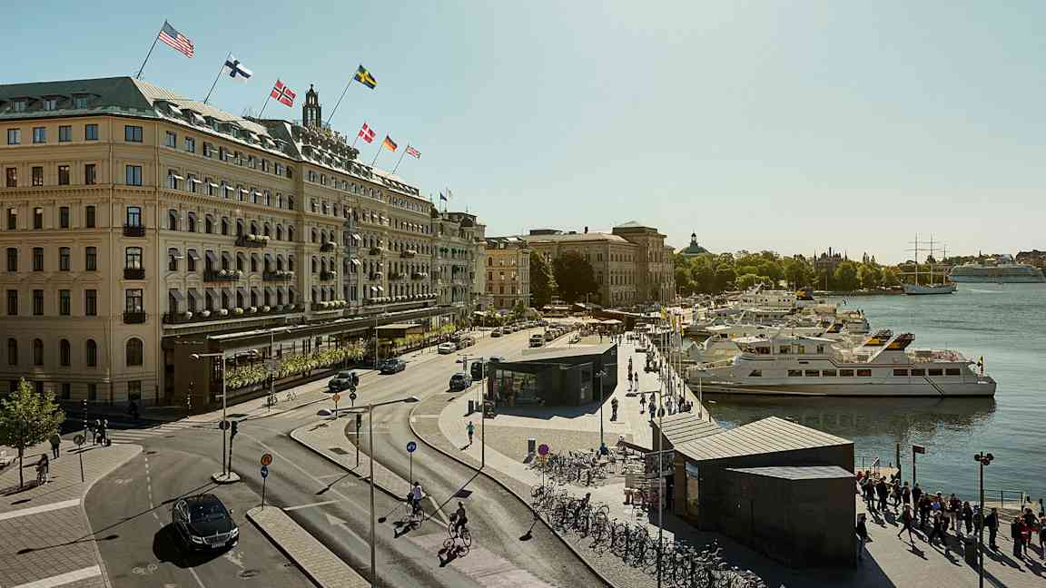 Utsikt over en by med en gate, bygninger med flagg og båter ved en brygge. (AI-generert tekst)