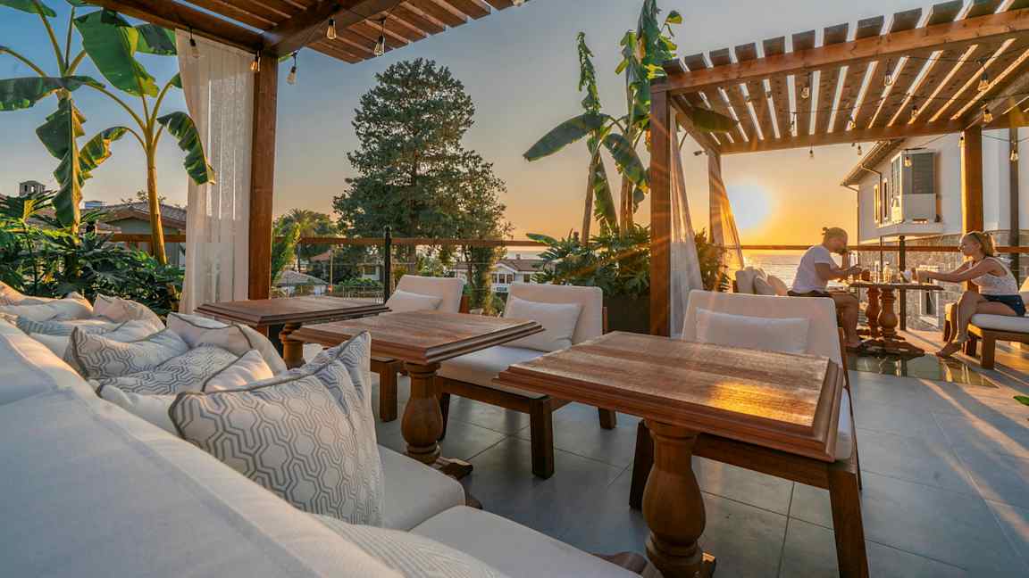 Uteområde med trepergola, sitteplasser og utsikt ved solnedgang. (AI-generert tekst)