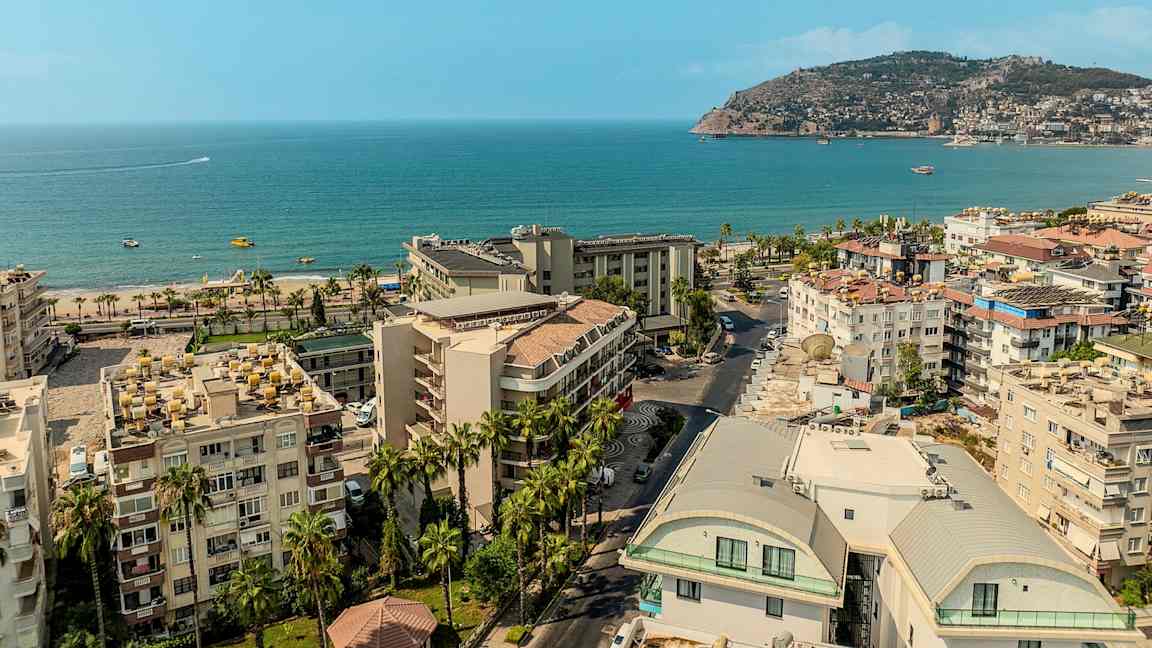 Utsikt over en kystby med bygninger, strand og hav. (AI-generert tekst)