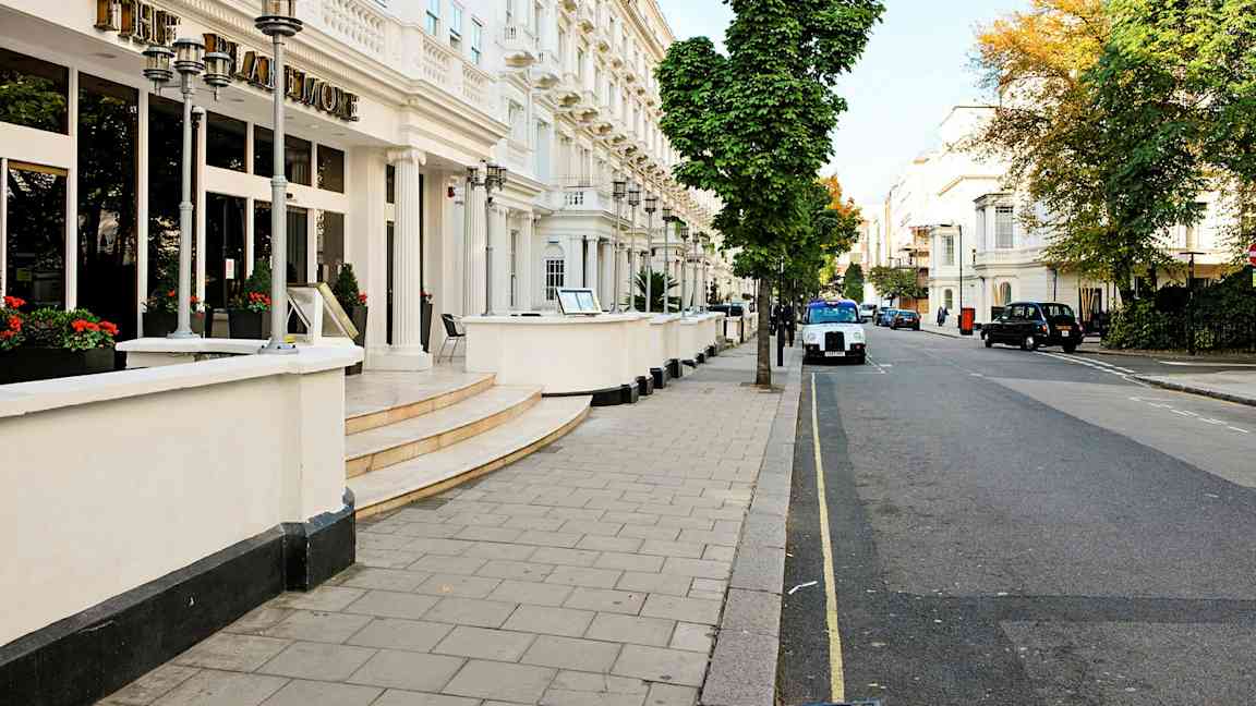 Fasade av et hotell ved en gate kantet med trær. (AI-generert tekst)