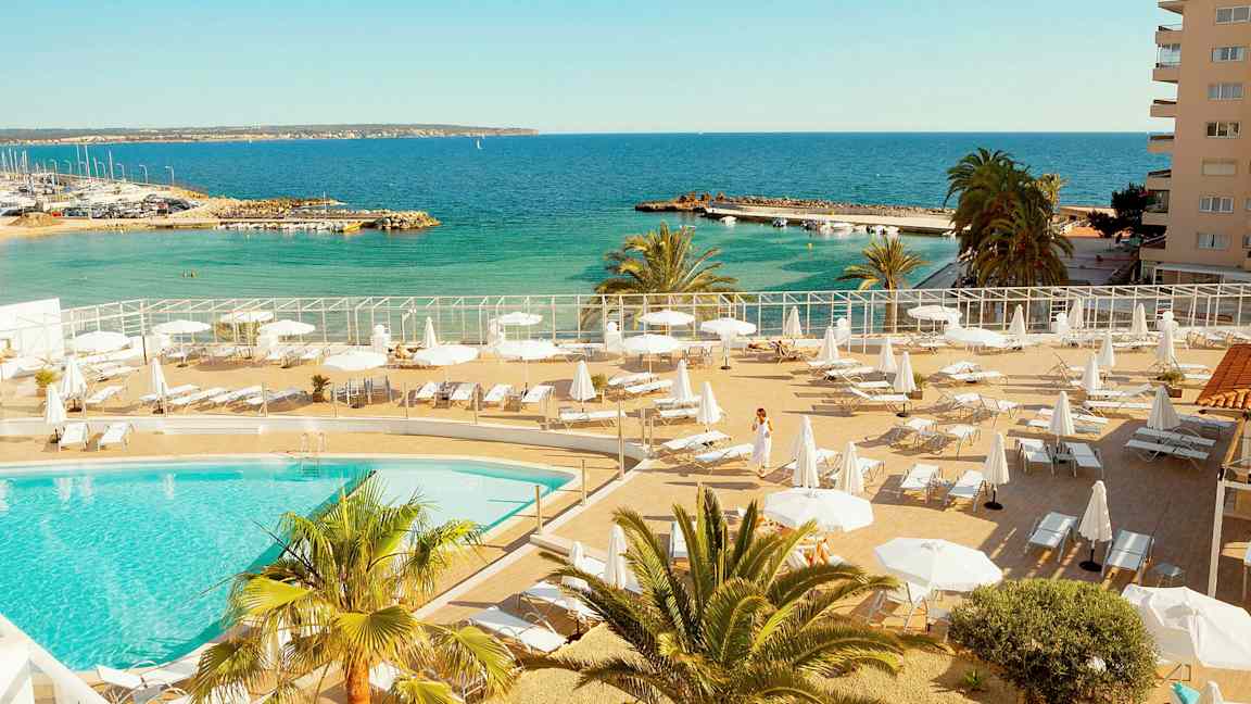 Bassengområde med solsenger og parasoller nær havet. (AI-generert tekst)