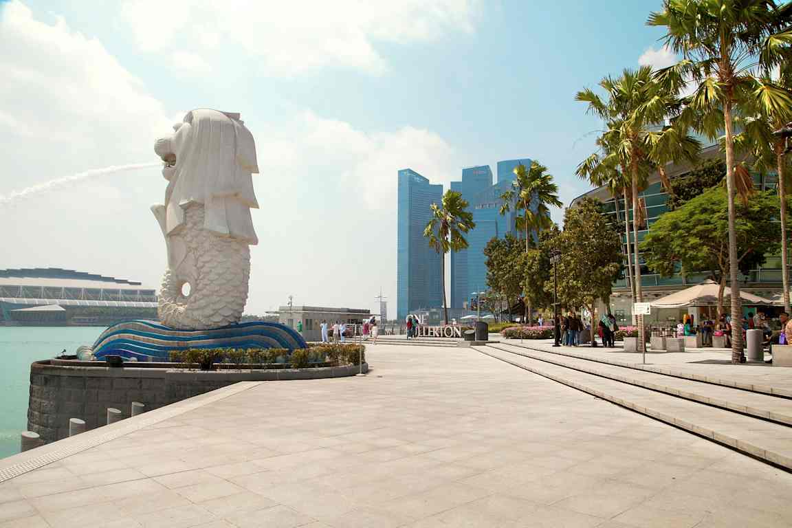 Bilde av Merlion-statuen i Singapore med fontene, omgitt av moderne arkitektur og palmer. (AI-generert tekst)