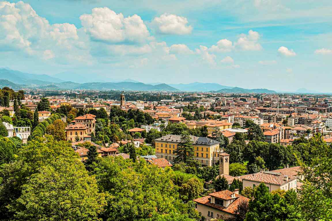 Byutsikt med bygninger, trær og fjell i bakgrunnen. (AI-generert tekst)