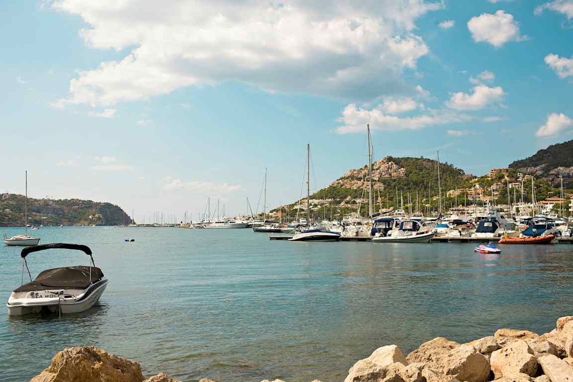 Bilde av en havn med båter og fjell i bakgrunnen. (AI-generert tekst)