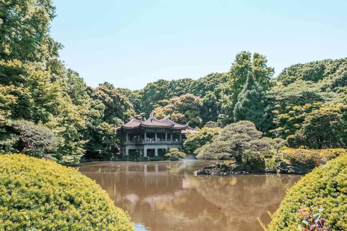 En kinesisk paviljong ved en dam i en frodig park. (AI-generert tekst)