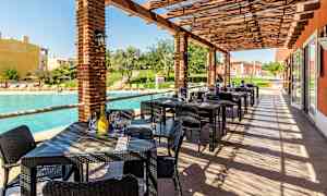 Utendørs servering med bord og stoler ved et basseng. (AI-generert tekst)