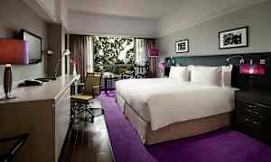 Hotellrom med en stor seng og moderne innredning, skrivebord og stol samt en utsikt gjennom et stort vindu. (AI-generert tekst)