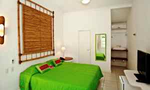 Et lyst soverom med en grønn seng, et speil på veggen og bambusdekorasjon. (AI-generert tekst)