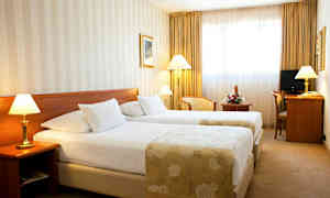 Et hotellrom med to enkeltsenger, lamper ved siden av sengene og et skrivebord med stol. (AI-generert tekst)