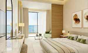 Et moderne hotellrom med havutsikt, møblert med en stor seng, en grønn sofa og en balkong. (AI-generert tekst)