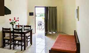 Et rom med et spisebord og stoler, en sovesofa, og en åpning som fører til en balkong. (AI-generert tekst)