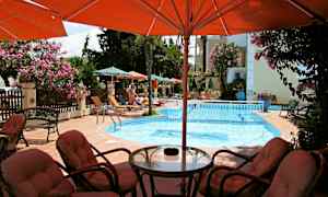 Et utendørs basseng med solsenger og parasoller rundt, samt sittegruppe i forgrunnen. (AI-generert tekst)