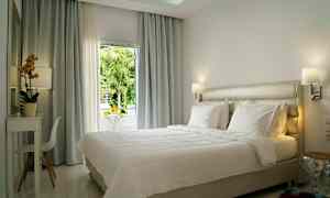 Lyst og moderne innredet hotellrom med en stor seng og vindu med utsikt. (AI-generert tekst)