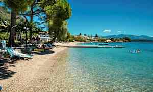 En strand med klart vann, solsenger og trær. (AI-generert tekst)