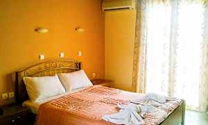 Et soverom med en dobbeltseng, oransje sengetøy og to håndklær dekorert på sengen. (AI-generert tekst)