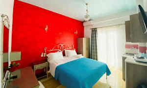 Et hotellrom med en dobbeltseng, rød veggdel og lyseblåt sengeteppe. (AI-generert tekst)