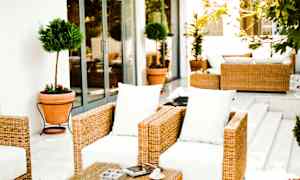 Utemøbler med rotting og hvite puter på en terrasse. (AI-generert tekst)