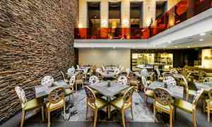 Interiør av en restaurant med stoler og bord, samt en vegg av stein. (AI-generert tekst)