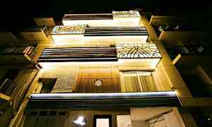 Leilighetsbygg sett nedenfra med nattbelysning. (AI-generert tekst)