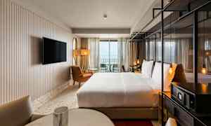 Hotellrom med dobbeltseng, sittemøbler og TV, samt balkong med utsikt. (AI-generert tekst)