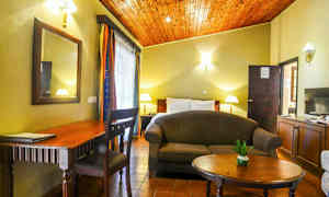 Et rom med seng, sofa, bord, skrivebord og dekorasjoner. (AI-generert tekst)