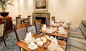 Et pent dekket rom med trestoler og dekkede bord. (AI-generert tekst)