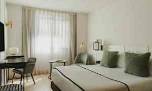 Et moderne møblert rom med en seng, skrivebord, stol og vindu med tynne gardiner. (AI-generert tekst)