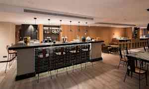 En moderne bar med høye stoler rundt en bardisk og et velutformet interiør. (AI-generert tekst)