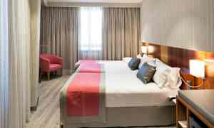 Hotellrom med to separate senger, enkle moderne møbler og et vindu i bakgrunnen. (AI-generert tekst)