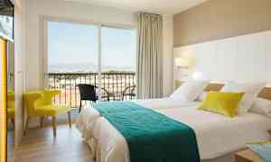 Et hotellrom med to senger, en stol og en balkong med utsikt. (AI-generert tekst)