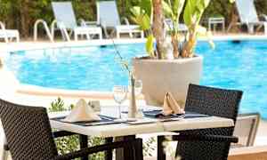 Et dekket bord ved et basseng, omgitt av solsenger. (AI-generert tekst)