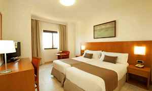 Et hotellrom med to enkeltsenger og trepanel på veggen. (AI-generert tekst)