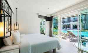 Hotellrom med oppredd seng og utsikt over et basseng utenfor. (AI-generert tekst)