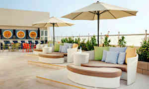 En terrasse med moderne sittegrupper, parasoller og en dekorativ bar i bakgrunnen. (AI-generert tekst)