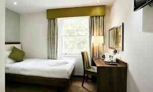 Hotellrom med enkeltseng, vindu, skrivebord og stol. (AI-generert tekst)