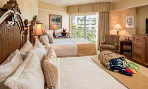 Hotellrom med to senger, elegant interiør og lys fra et vindu med utsikt over grøntområder. (AI-generert tekst)