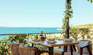 Uteservering med bord og stoler ved sjøen. (AI-generert tekst)